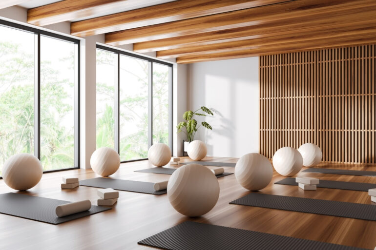 White and wooden yoga studio corner with mats and fitballs