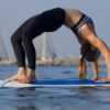 woman in a backbend yoga pose while on surfboard