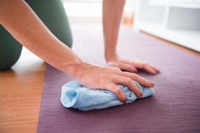 Woman Uses Hand Towel to Wipe Yoga Mat Clean at Home