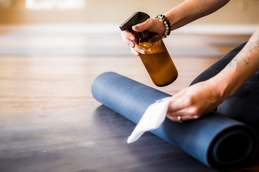 Woman cleaning yoga mat with sanitizer