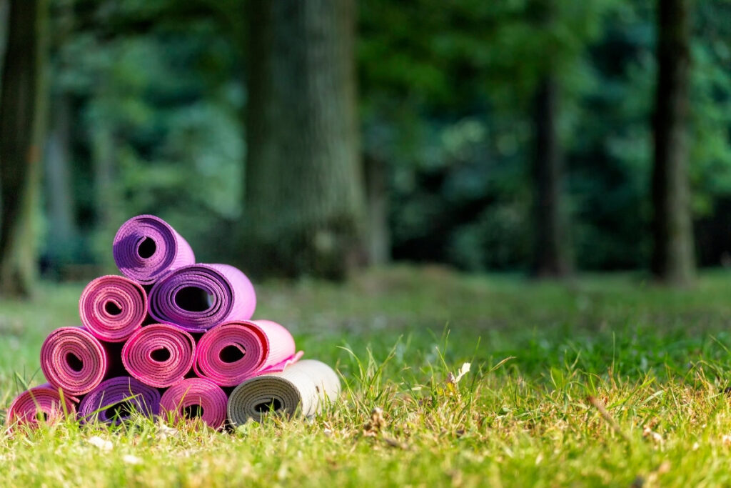 rolled colorful yoga mats outdoors in grass