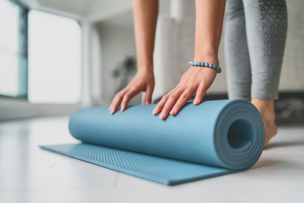 woman rolling yoga mat indoors