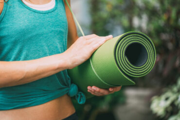 yoga teacher holding travel yoga mat