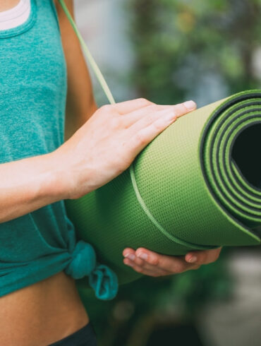 yoga teacher holding travel yoga mat