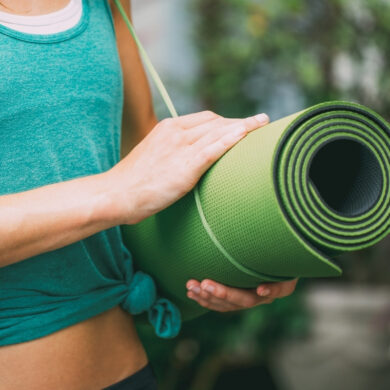 yoga teacher holding travel yoga mat